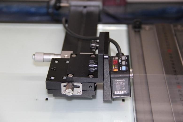 Mắt quang Panasonic trên bàn vi chỉnh: đọc dấu in để xác định chiều dài mỗi bản.